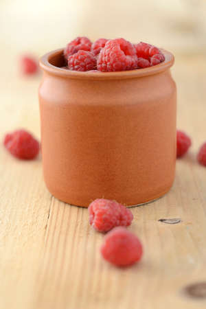 Bowl of Raspberries on textured wood background. Shallow depth of field.の写真素材