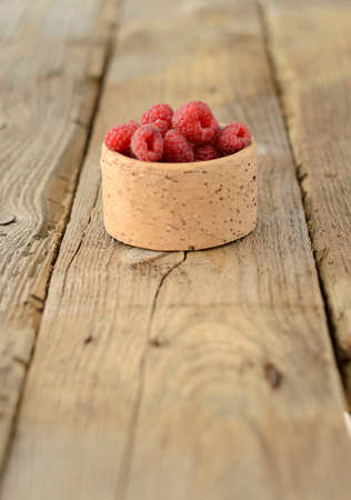 Bowl of Raspberries on textured wood background. Shallow depth of field.の写真素材
