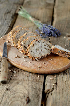 Slices of grain bread, a knife and lavender flower on wood table. Shallow depth of field.