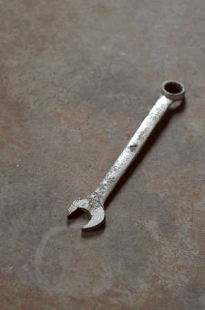 Rusty hand wrench tool and on rusty metal background. Above view.
