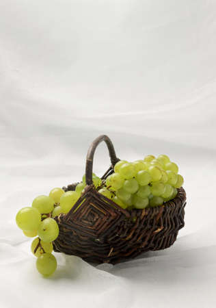 Green grapes in basket on natural textured canvasの写真素材