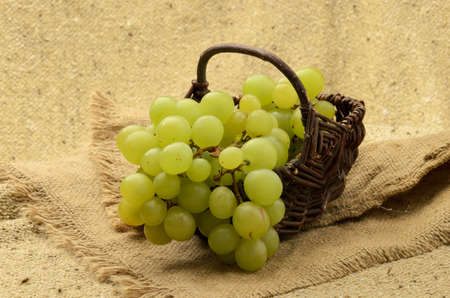 Green grapes in basket on natural textured canvasの写真素材