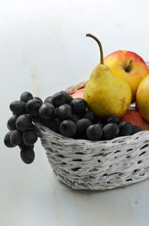 Grapes, pears and apples in basket on wooden backgroundの写真素材