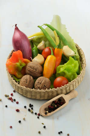 Peppers, walnuts, garlic, green beans and red onion in basket on wooden backgroundの写真素材