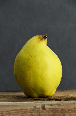 Fresh ripe quince on wooden background. Dark and moody atmosphereの写真素材
