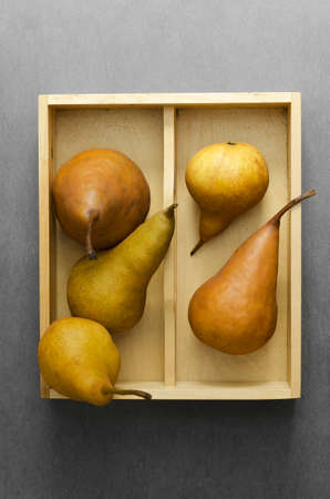 Multiple ripe pears in wooden box over dark grey backgroundの写真素材