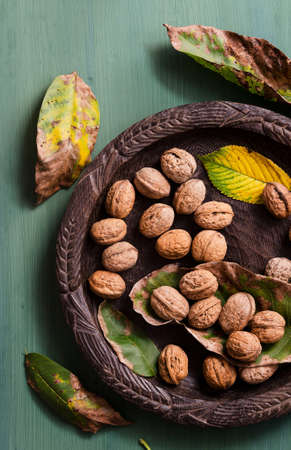 Walnuts in rustic bowl over green background. Above view.の写真素材