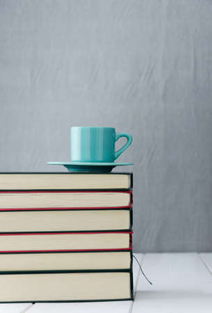 Blue coffee cup on stack of booksの写真素材