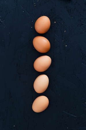Eggs arranged in straight line over dark background. Overhead viewの写真素材