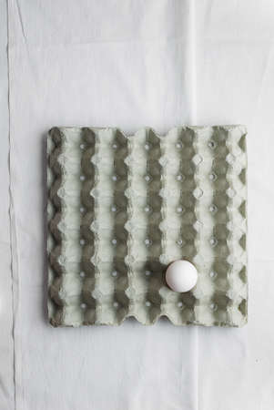 Signle egg in formwork over white cloth, above viewの写真素材