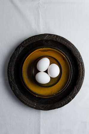 Eggs on brown plates over white cloth, above viewの写真素材