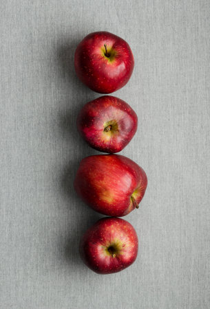 Ripe red apples in a row over gray cloth, above viewの写真素材