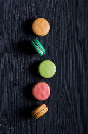 Macaroons biscuits in a row over black wooden tableの写真素材