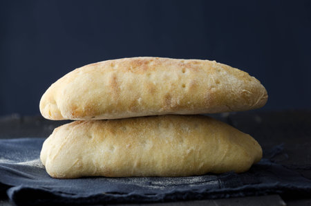 Two ciabatta bread over dark wooden table