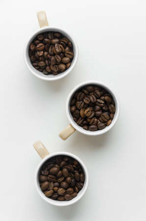Coffee beans in cups over white table, above viewの写真素材