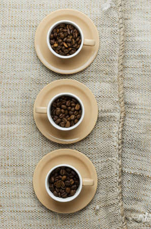 Coffee beans in cups over rustic burlap, above viewの写真素材