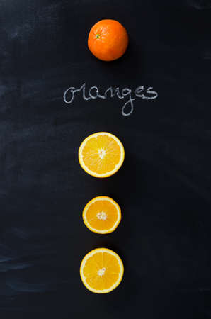 Orange fruits over black chalkboard with handwritten "oranges" word , above viewの写真素材