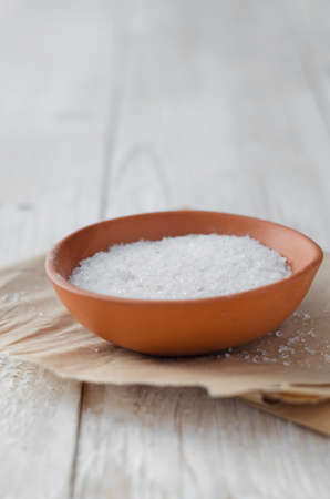 Close up of a bowl with salt over white wooden tableの写真素材