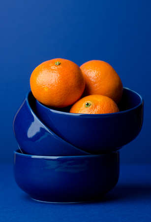 Multiple clementines in a blue bowl, over dark blue backgroundの写真素材