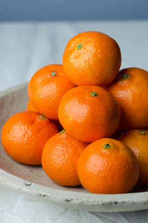Multiple clementines in a ceramic rustic bowlの写真素材