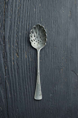 Single silver spoon over dark black wooden table, top viewの写真素材
