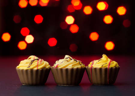 Chocolate Cup Cake over black table with red lights bokeh in the backgroundの写真素材