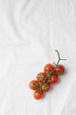 Cherry tomatoes over white cloth, above view with lots of copy spaceの写真素材