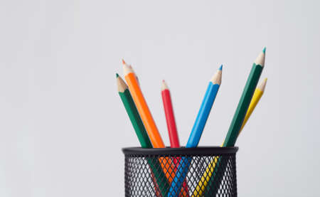 Wooden colored crayons in a pencil box holder over white background