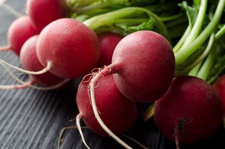 Close up of Red Radishes over black wooden tableの写真素材