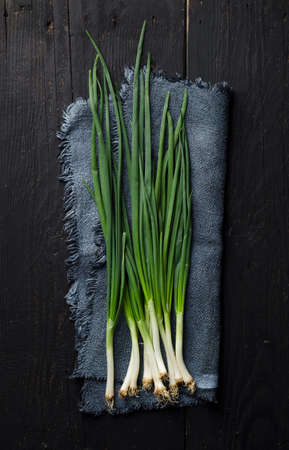 Spring onions over black wooden table, above viewの写真素材