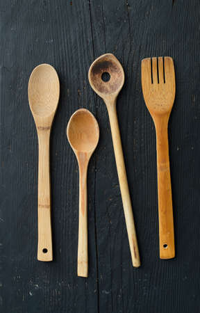 Kitchen wooden utensils over black wooden table, above viewの写真素材