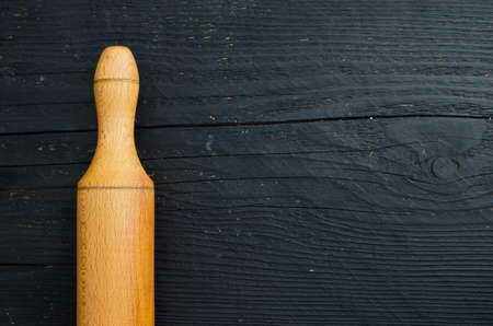 Rolling wooden pin detail over black wooden table, horizontal and above view with copy space for text or other designの写真素材