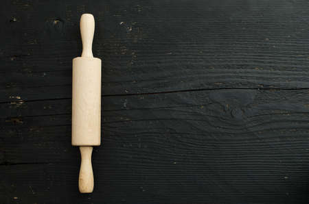 Rolling wooden pin over black wooden table, horizontal and above view with copy space for text or other designの写真素材