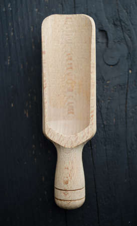 Wooden scoop close up over black wooden table, above view.の写真素材