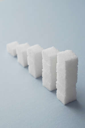 Concept: Ascending stacks of sugar cubes over blue background. This in a concept for high risk of diabetes or other diseases caused by excessive consumption of sugarの写真素材