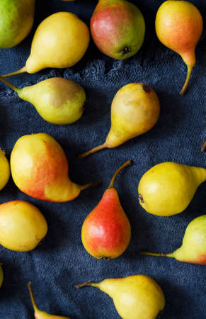 Multiple colorful pears over rustic blue cloth, above viewの写真素材