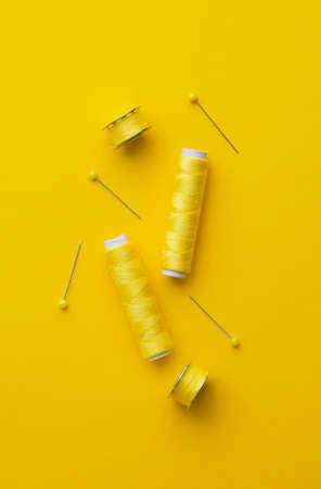 Colorful yellow thread spools over bright yellow background, above viewの写真素材