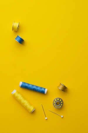Colorful thread spools over bright yellow background, above view with space for text or other designの写真素材
