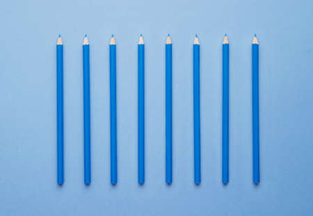 Blue crayons organized in a row over blue background, above viewの写真素材