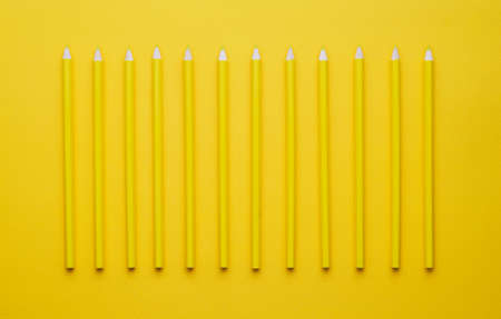 Yellow crayons organized in a row over yellow background, above viewの写真素材