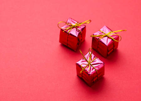 Small Red Christmas Gift Boxes over red background with space for text or other desingsの写真素材