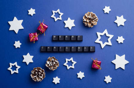 Merry Christmas text made of keyboard keys and other christmas decoration over dark blue background, above viewの写真素材