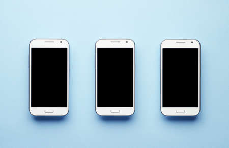 Three White Smart Phone over blue background, top viewの写真素材