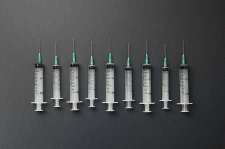 Syringes organized in a row over dark grey background, top viewの写真素材