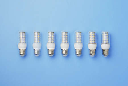 Energy saving SMD led light bulbs organized in a row over blue background, top view.の写真素材