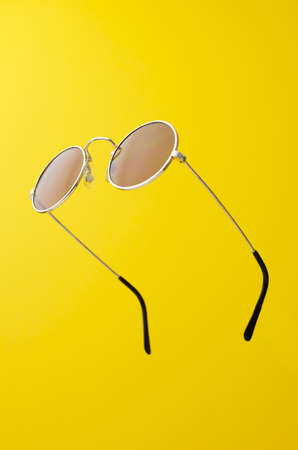 Round Sunglasses in the air over yellow background