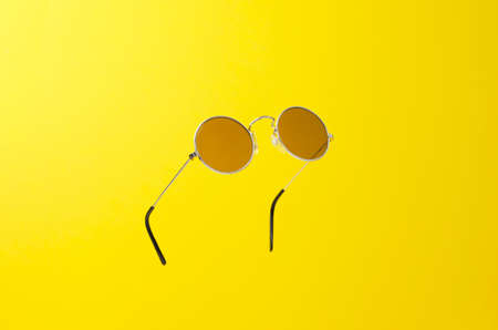Round Sunglasses in the air over yellow backgroundの写真素材