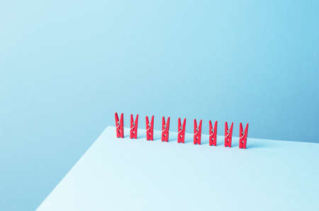 Red laundry clips organized in a row over blue backgroundの写真素材
