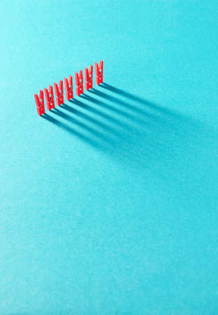 Red laundry clips organized in a row over blue backgroundの写真素材