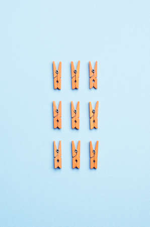 Orange Laundry clips organized over blue background, top view